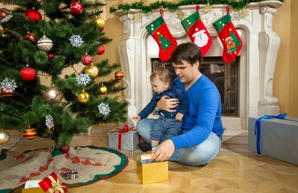 Pojke med sin far som öppna julklappar på golvet vid liv — Stockfoto