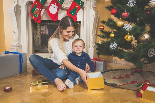 Мать с ребенком на полу, глядя на рождественские подарки — стоковое фото