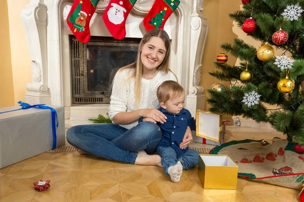 Menino com sua mãe abrindo caixas de presente sob a árvore de Natal — Fotografia de Stock