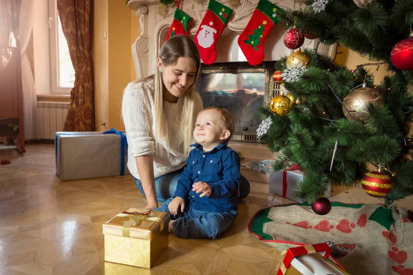 Madre y bebé con regalos de Navidad en el suelo en la sala de estar —  Fotos de Stock