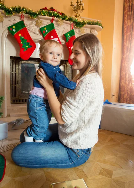 Mladá matka sedí s její chlapeček na podlaze na Vánoce tre — Stock fotografie