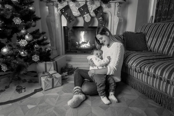 Black and white image of beautiful young mother sitting with her — Stock Photo, Image