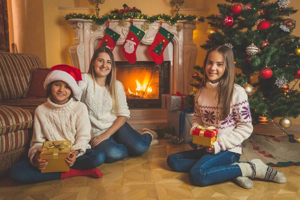 Mutter und zwei Tochter sitzen mit Weihnachtsgeschenken auf dem Boden — Stockfoto