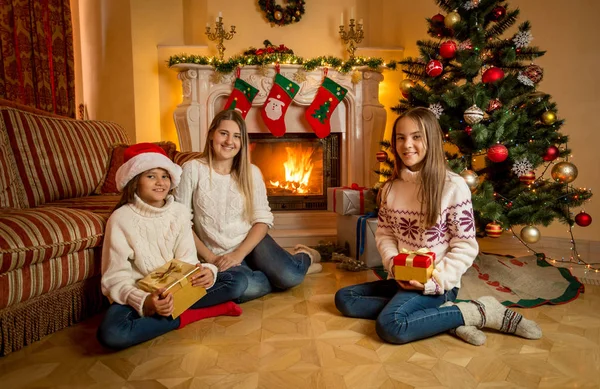 Feliz joven madre sentada con dos hijas en el suelo al lado de b —  Fotos de Stock