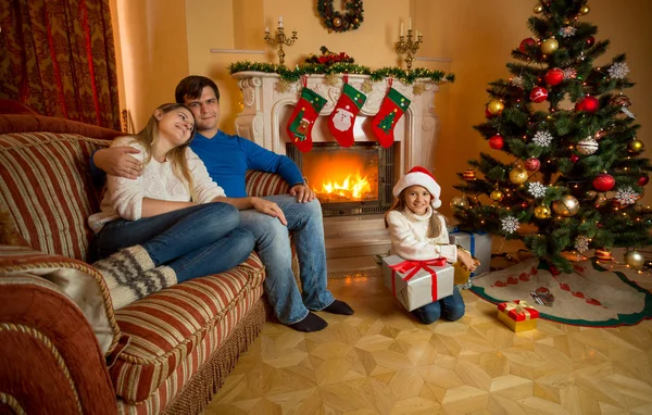 Feliz familia joven relajante cerca de la chimenea en Navidad —  Fotos de Stock