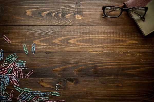 Wooden background with notebook and colorful paperclips. Place f — Stock Photo, Image