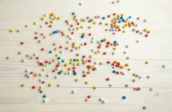 Барвисті круглі цукерки, що лежать на білих дерев'яних дошках — стокове фото