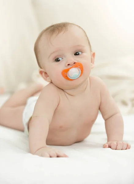 Lindo bebé con chupete usando pañales acostado en la cama — Foto de Stock