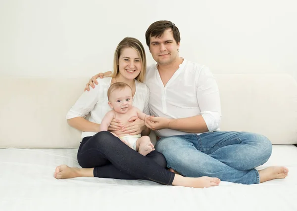 Happy young family posing with baby son on bed — Stock Photo, Image