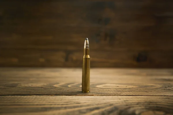 Closeup image of riffle bullet on old wooden desk — Stock Photo, Image