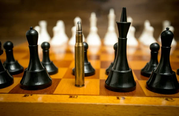 Big riffle bullet in row of black chess pieces. Concept of gun p — Stock Photo, Image