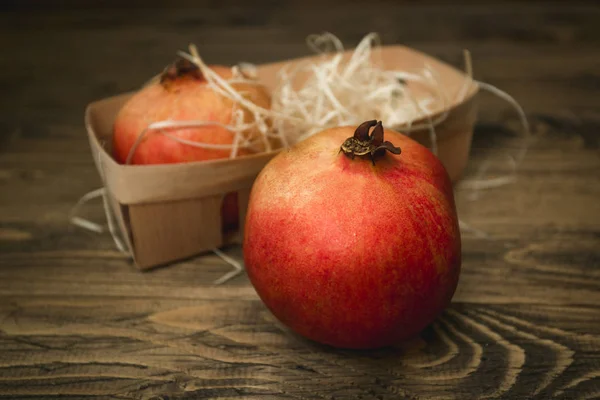 Nahaufnahme eines ganzen Granatapfels, der auf einem alten Holztisch liegt — Stockfoto