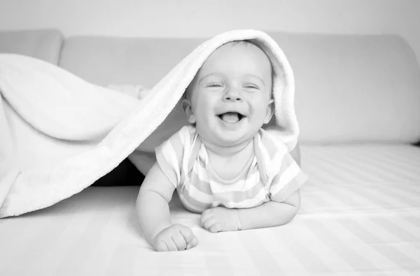 Retrato en blanco y negro de lindo bebé acostado en la cama debajo de la — Foto de Stock