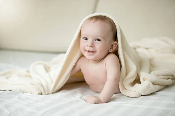 Porträt eines überraschten Jungen, der unter einer Decke auf dem Bett liegt — Stockfoto