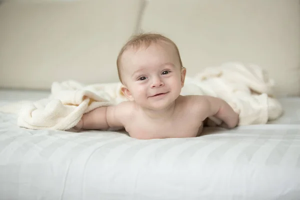 Niedlicher kleiner Junge liegt auf dem Bett unter einer großen weißen Decke — Stockfoto