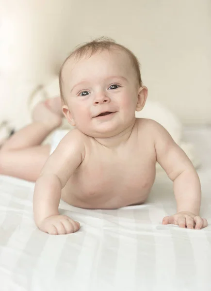 Retrato de bebê sorridente bonito deitado sob cobertor na cama — Fotografia de Stock