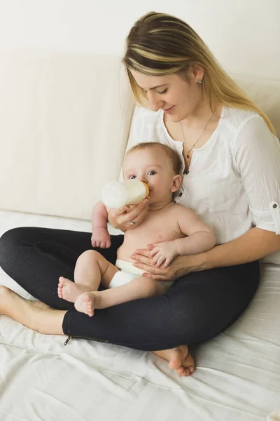 Happy young mother and her baby eating from bottle — Stock Photo, Image
