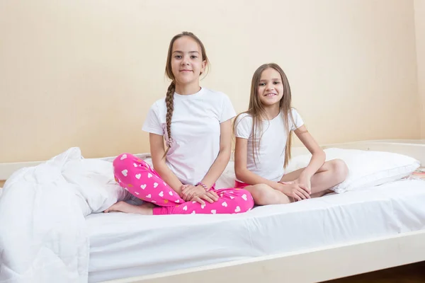 Två flickor i pyjamas som sitter på sängen — Stockfoto