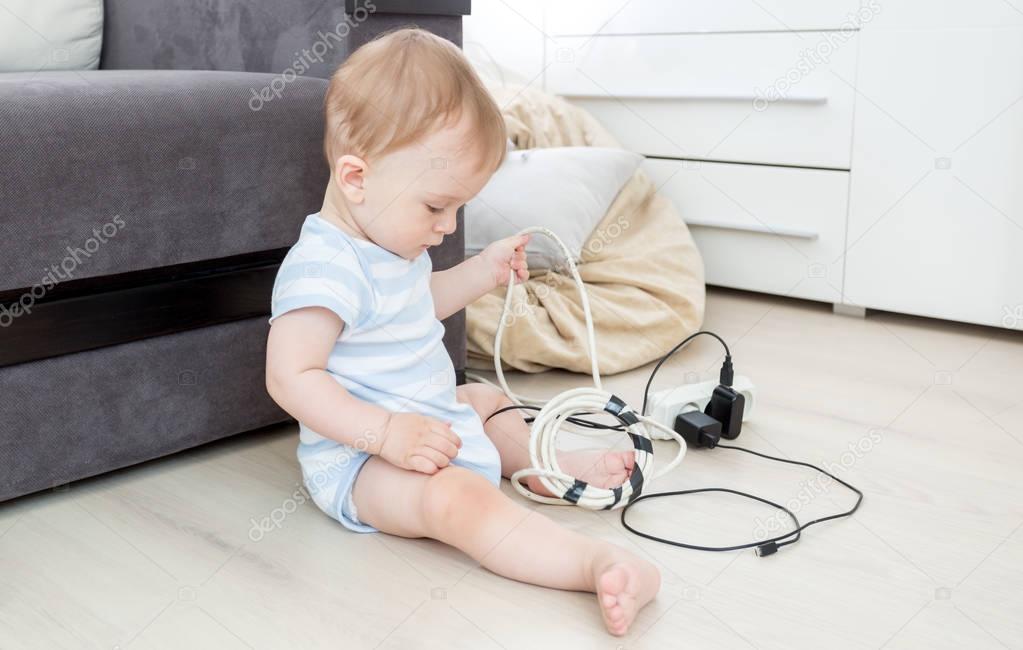 Baby boy pulling cables from electrical extension