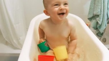 Şirin yürümeye başlayan çocuk banyo oyuncakları ile oynarken