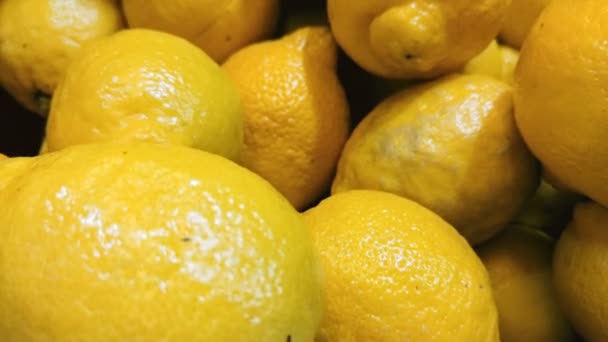 Primo piano dolly shot di limoni freschi gialli sdraiati sul bancone del negozio di alimentari — Video Stock