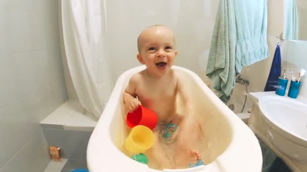 Happy cheerful baby boy splashing in small plastic bathtub — Stock Video