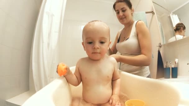 Slow motion video of young mother washing her baby son in bath — Stock Video