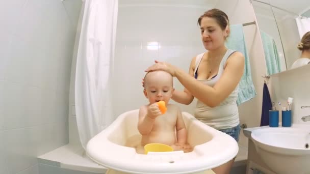 Joven madre lavando la cabeza de los niños en el baño — Vídeo de stock