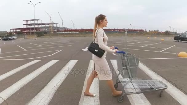 Filmagem em câmera lenta de uma jovem caminhando para o supermercado no estacionamento — Vídeo de Stock