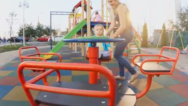 Slow motion video of cute baby riding on carousel at playground — Stock Video