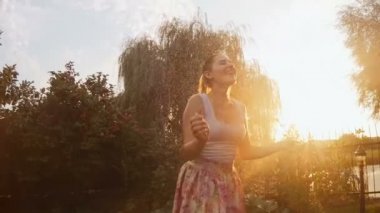 Yaz yağmuru altında günbatımında dans mutlu neşeli kadın ağır çekim görüntüleri