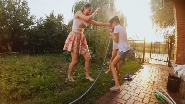 Vídeo en cámara lenta de familia feliz jugando con manguera de jardín en el patio trasero — Vídeos de Stock