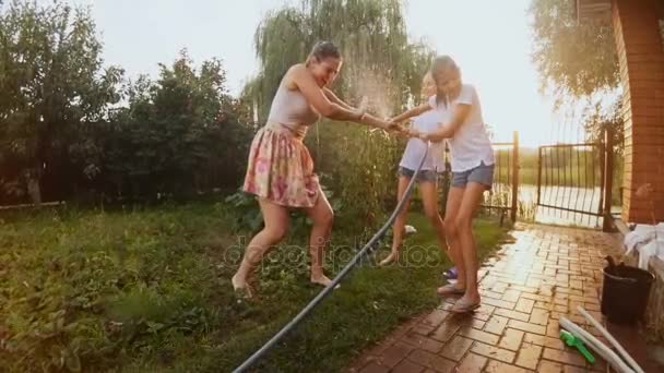 Vídeo em câmera lenta de meninas felizes brincando no jardim com mangueira de água — Vídeo de Stock