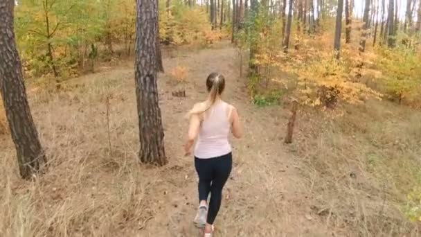 Filmagem em câmera lenta do ponto alto da linda mulher loira correndo na floresta de outono — Vídeo de Stock