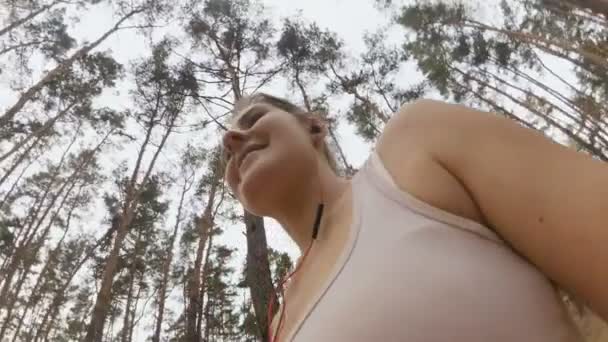 Вид с камеры, прикрепленной к женской руке, бегущей по лесу — стоковое видео