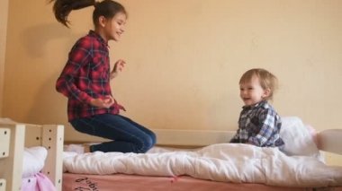 Şişme yatak odası, genç kız kardeşiyle atlama mutlu yürümeye başlayan çocuk
