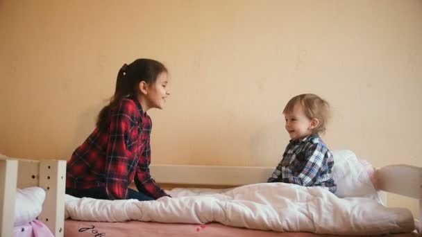Медленная съемка веселого мальчика, прыгающего с сестрой на кровати — стоковое видео