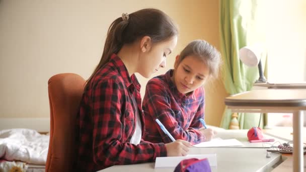 4k metraje de dos hermanas adolescentes hablando y sonriendo mientras hacen la tarea — Vídeos de Stock