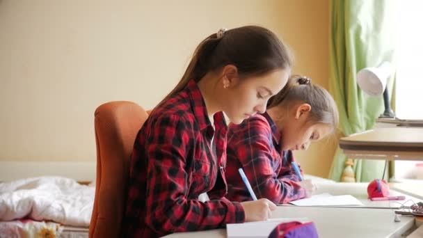 Dos chicas adolescentes hablando mientras hacen la tarea detrás del escritorio en el dormitorio — Vídeos de Stock