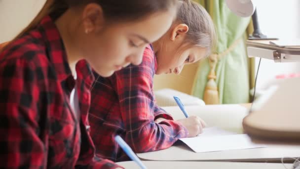 4 k video van twee tienermeisjes voorbereiding huiswerk achter bureau op groot venster — Stockvideo