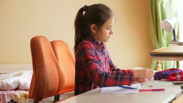 Девочка-подросток слушает музыку в наушниках, делая домашнее задание в спальне — стоковое видео