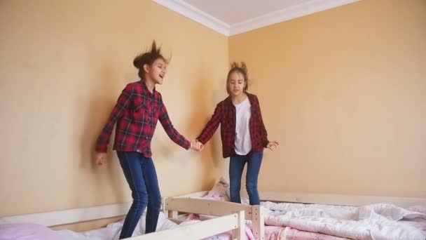 Slow motion video av glad tonårsflickor hoppning på madrass på sovrum — Stockvideo