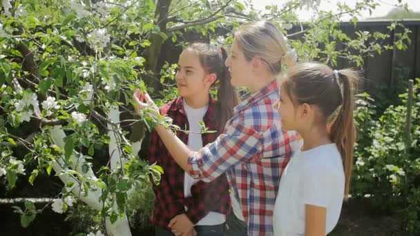 Video al rallentatore di una giovane madre che insegna alle sue figlie in giardino — Video Stock