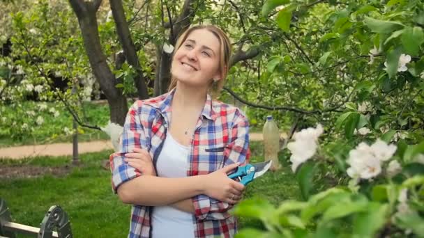 Zeitlupenvideo einer glücklich lächelnden Frau, die auf einem Obstgarten posiert und in die Kamera blickt — Stockvideo
