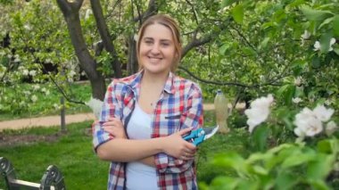 Yavaş çekim mutlu gülümseyen kadın bahçede budama makası ile poz