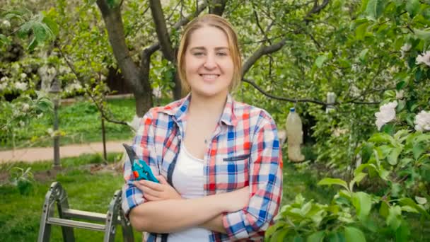 Portrait de heureuse femme riante avec des outils de jardinage dans le verger — Video