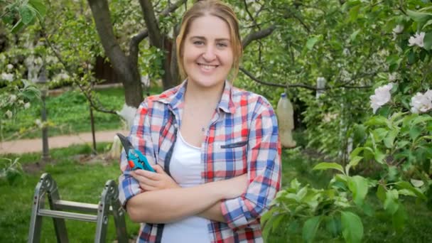 Beautiful smiling woman with gardening tools looking at camera — Stock Video