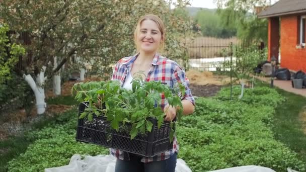 Gelukkig lachende vrouw die zich voordeed op de tuin van de achtertuin met tomaat zaailing — Stockvideo