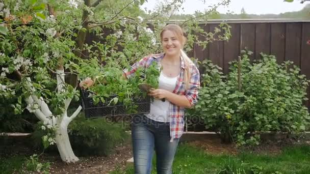 Vidéo au ralenti de la jeune femme marchant avec des semis dans un plateau — Video