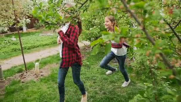 Повільні кадри двох щасливих сестер, що біжать у саду на задньому дворі — стокове відео